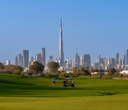 A fairway at Dubai Hills Golf Club, with the Dubai skyline and Burj Khalifa behind it